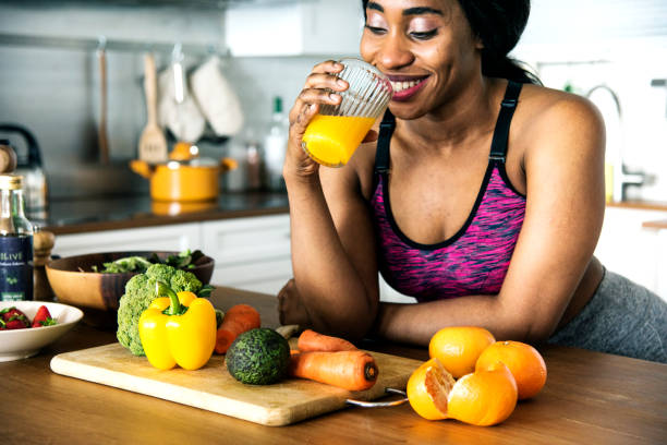 la donna nera beve succo d'arancia - women juice drinking breakfast foto e immagini stock