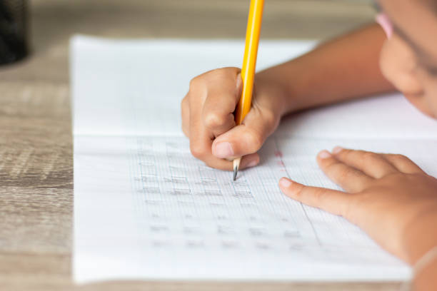 istock A little girl use a yellow pencil writing in a notebook 979026454
