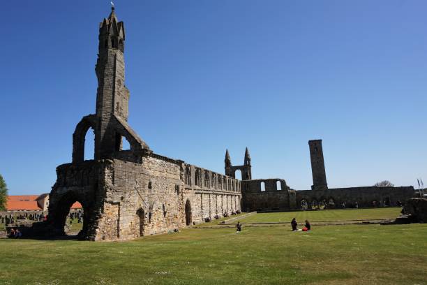 St Andrews, Scotland - June 05, 2018: View of the ruins of the 12th century St Andrews Cathedral on a warm June day. A number of visitors are relaxing on the grass or on the benches lining the wall. This popular site is free to enter and wander around.
