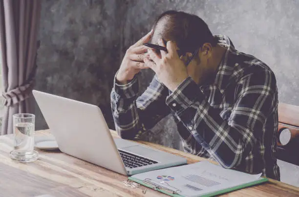 Photo of Man feel stressed and tired to business in laptop computers at workplace.