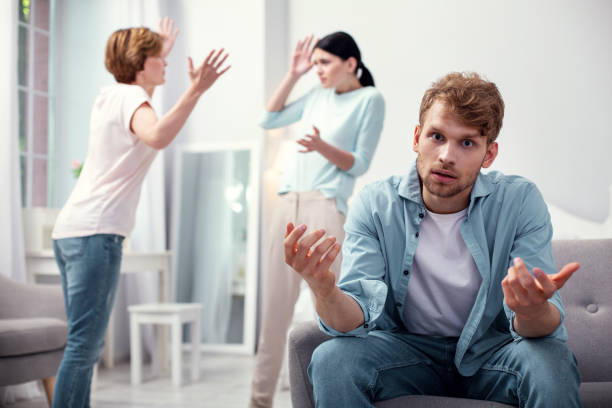 Cheerless sad man not knowing what to do I need advice. Cheerless sad man not knowing what to do while listening to family quarrel mother in law stock pictures, royalty-free photos & images