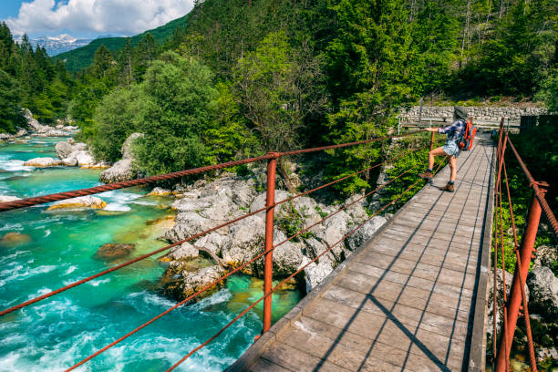 A young woman stands and looks at a hanging bridge, River Soca, Primorska, Slovenia, Europe A young woman stands and looks at a hanging bridge, River Soca, Primorska, Slovenia, Europe,no logos,Nikon D850 soca valley stock pictures, royalty-free photos & images