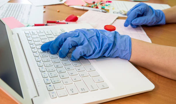 istock Doctor's hand in glove typing on laptop keyboard 979043652