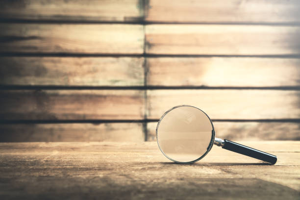 istock Magnifying glass on wooden table. Search and discover 979048358