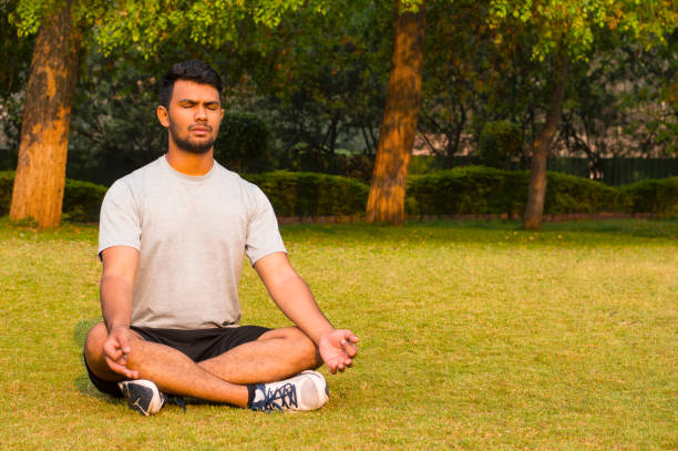 istock Young guy doing yoga lotus pose in a park 979049340