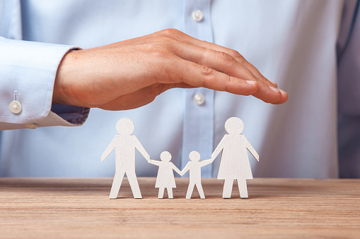 Medical or travel insurance. Man covers the family with his hands from his father, mother, son and daughter.