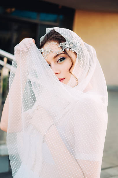istock Beautiful eastern style bride with white veil and hairpiece posing outdoors at sunset. 979054726