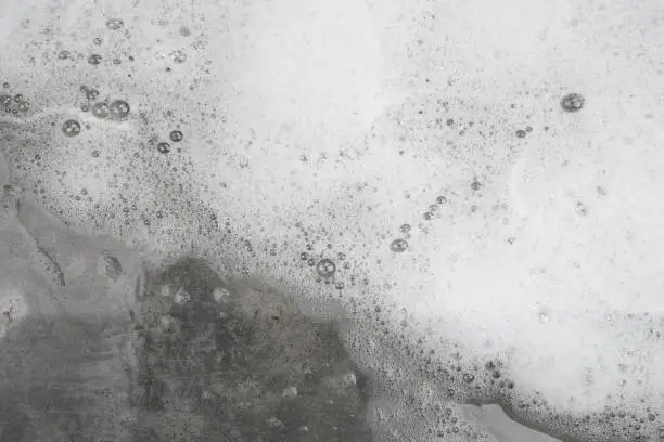 Photo of White bubble foam from washing on concrete floor on top view