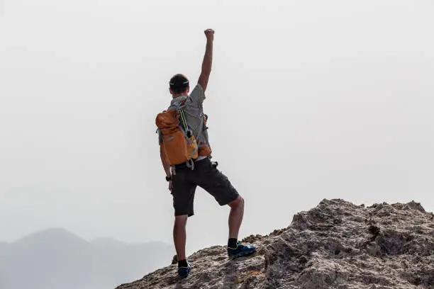 Success and achievement business concept with man celebrating with hand up, arm raised outstretched looking at inspirational landscape view, Greece.