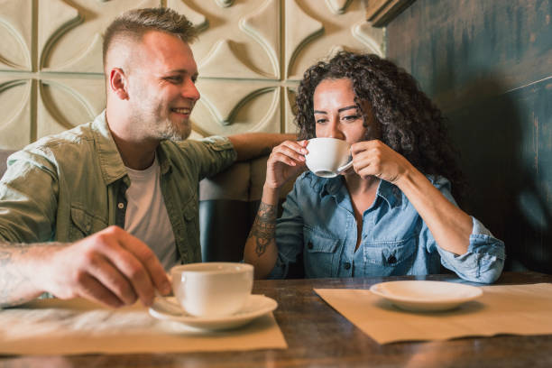 istock Happy young couple is drinking coffee and smiling while sitting at the cafe 979098282