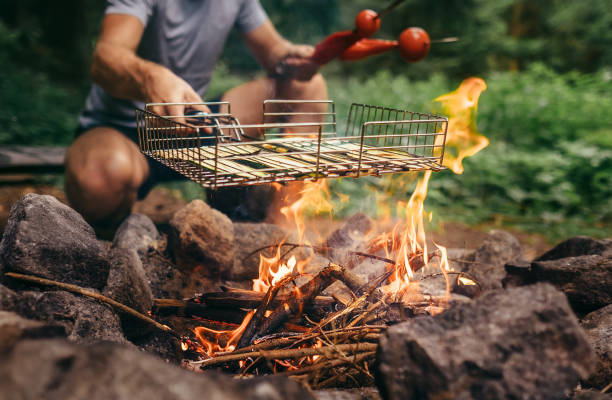 istock Summertime leisure concept image: man cooks a vegetabels on campfire 979109596