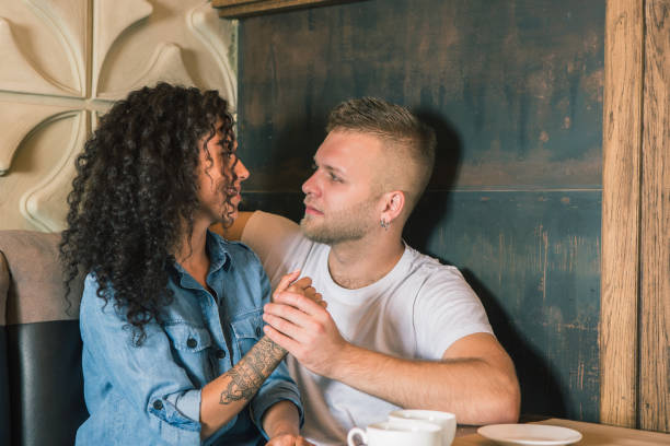 istock Happy young couple is drinking coffee and smiling while sitting at the cafe 979114320
