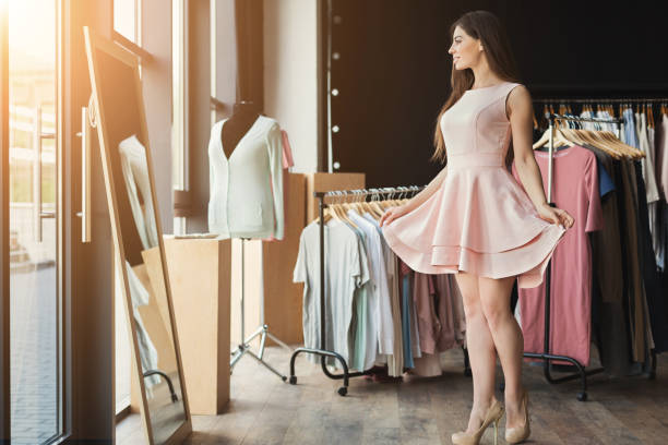 smiling woman trying on dress at mirror - adult variation boutique occupation imagens e fotografias de stock