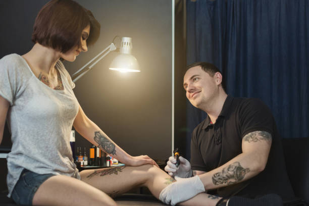 istock Professional tattoo artist making tattoo on leg 979135070
