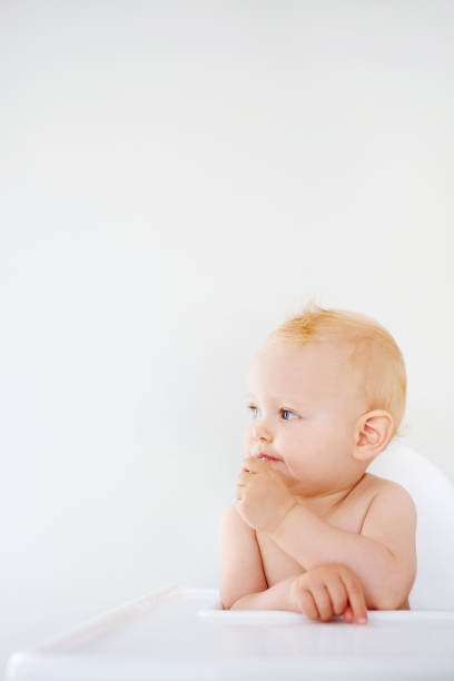 Shot of an adorable baby girl sitting in a high chair at home and eating a snack