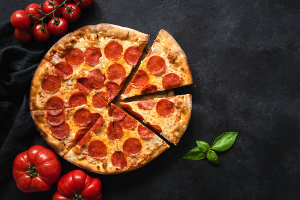 Pepperoni pizza on black concrete background Pepperoni pizza on black concrete background. Top view with copy space. Tasty sliced pepperoni pizza pepperoni pizza stock pictures, royalty-free photos & images