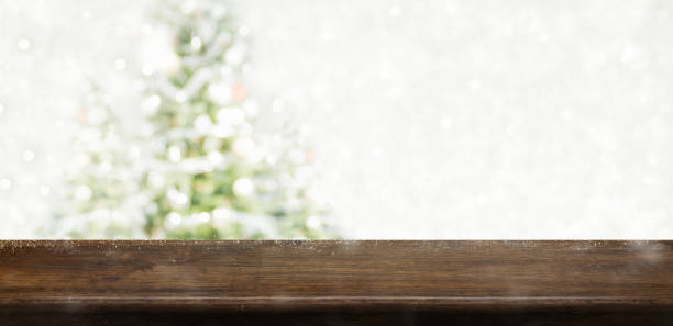 istock Empty dark brown wooden table top with abstract muted blur christmas tree and snow fall background with bokeh light,Holiday backdrop,Mock up banner for display or montage of product. 979176524