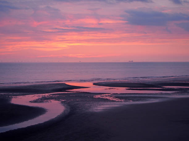 hermosa cerca de crepúsculo oscuro sobre un tranquilo mar plano con cielo púrpura y azul nubes reflejada en el agua en la playa - horizon over water england uk summer fotografías e imágenes de stock