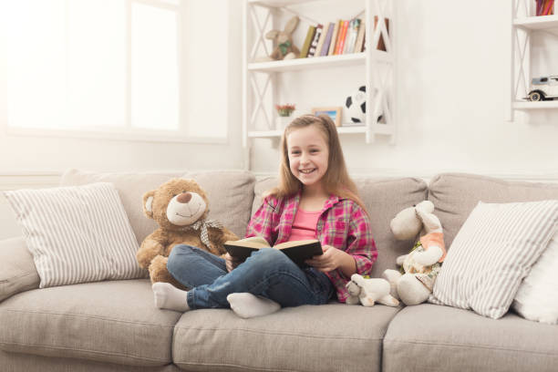 istock Happy little child reading book for her teddy bear 979207108