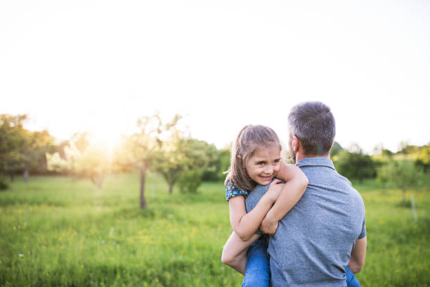 istock Father holding a small daughter in spring nature at sunset. 979216374