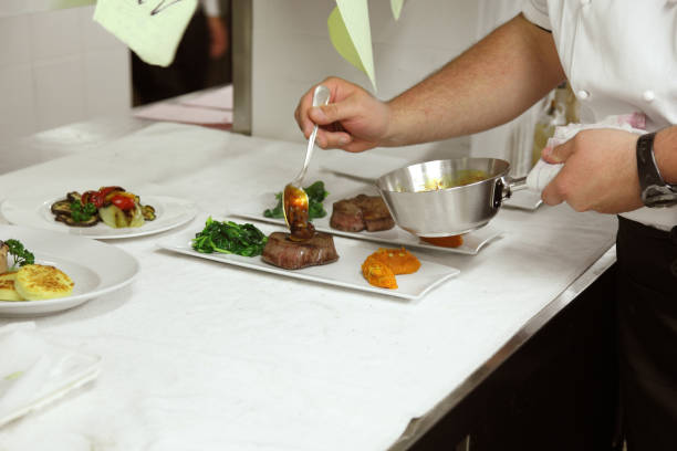 chef plating a meat dish with pumpkin and sauce