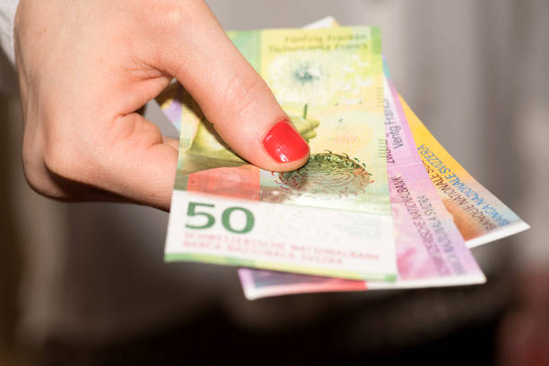 una donna tiene in mano banconote in franchi svizzeri - swiss currency switzerland currency wages foto e immagini stock