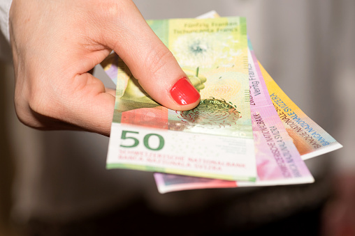 A woman holds Swiss franc banknotes in her hand