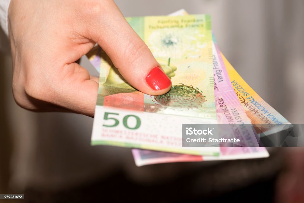 A woman holds Swiss franc banknotes in her hand A woman holding Swiss franc banknotes in her hand Swiss Currency Stock Photo