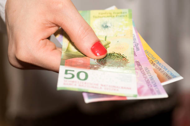 a woman holds swiss franc banknotes in her hand - swiss francs swiss currency switzerland finance imagens e fotografias de stock