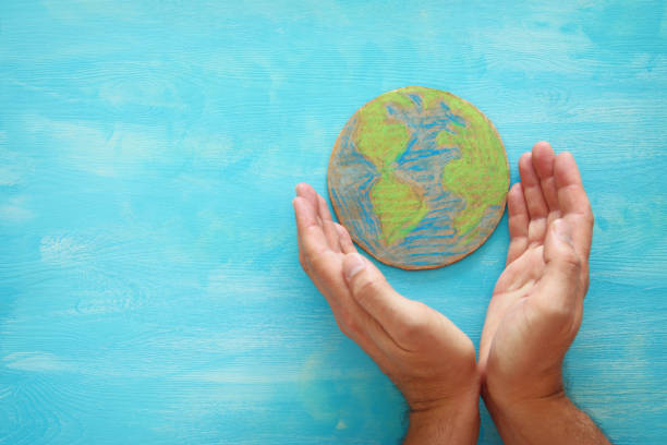 istock top view image of man hands holding earth globe over blue wooden background. 979237546