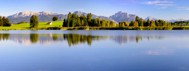 istock panorama scene in Bavaria with mountain range mirroring in lake Forggensee 979238510