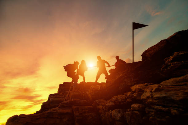 silhouette masculines et féminines randonneurs grimper sur la falaise de la montagne, aide et concept de travail d’équipe. - climbing adventure hiking assistance photos et images de collection