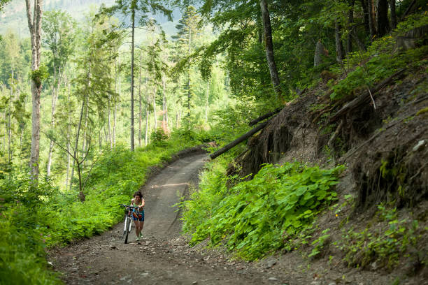 istock Biker pushes bicycle up in the green forest 979246644