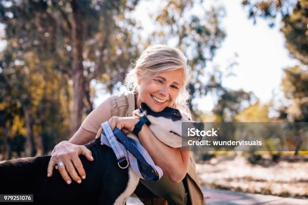 Affectionate Mature Woman Embracing Pet Dog In Nature Stock Photo - Download Image Now