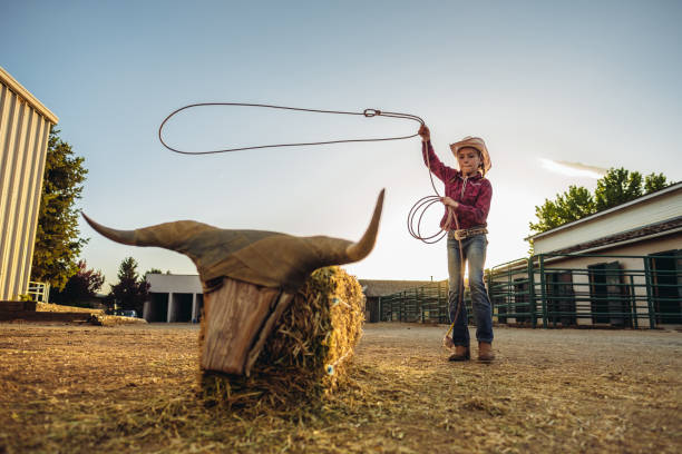 Portrait of young cowgirl practicing roping with lasso at the ranch.  Outside Salt Lake City, Utah.