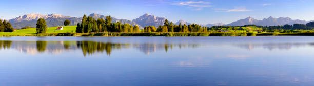 istock panorama scene in Bavaria with mountain range mirroring in lake Forggensee 979263198
