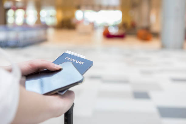 Unrecognizable international traveler holds smart phone and US passport.