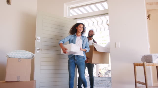 Slow Motion Shot Of Couple Carrying Boxes Into New Home On Moving Day