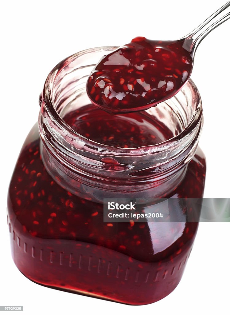 Raspberry confiture in a jar on a white background Raspberry confiture in glass with metal spoon isolated on white Berry Fruit Stock Photo