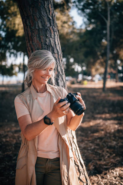 istock Female mature photographer on summer vacations using camera in nature 979303278