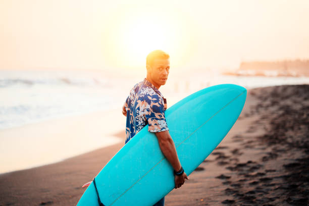 istock Surfer in hawaiian t-shirt walking with surf board 979304718