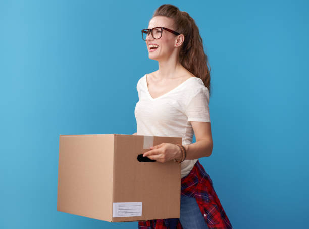 istock happy woman with cardboard box looking at copy space on blue 979305450
