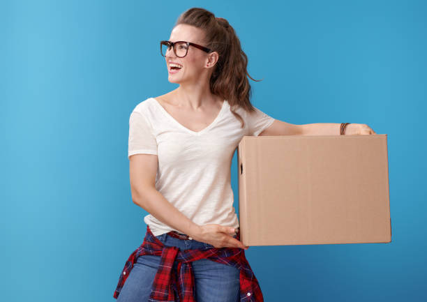istock happy woman with cardboard box looking at copy space on blue 979305636