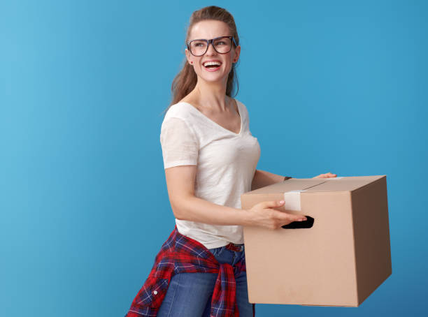istock happy modern woman with cardboard box looking back on blue 979306252