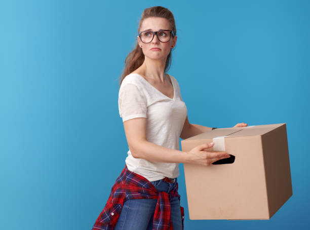 istock unhappy active woman with cardboard box looking back on blue 979306326