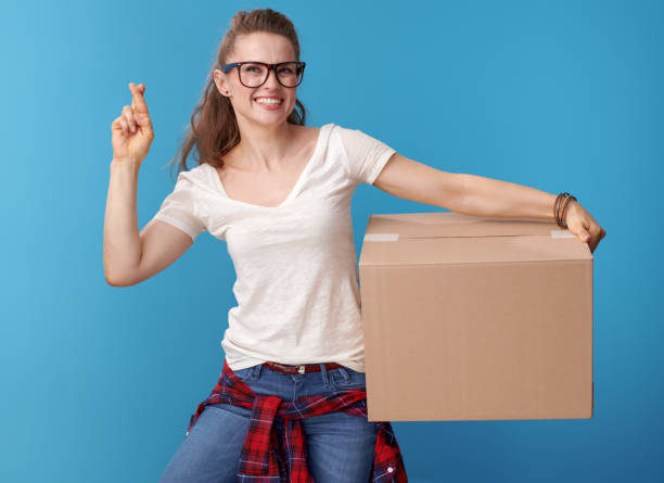 istock smiling hipster with cardboard box and crossed fingers on blue 979308540