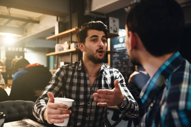istock Two Friends Drinking Coffee and Socialising in a Cafe 979315634