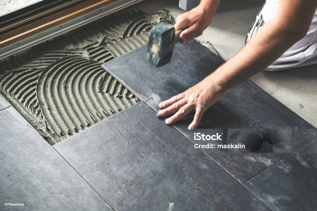 Worker placing ceramic floor tiles Worker carefully placing ceramic floor tiles on adhesive surface Tile Stock Photo