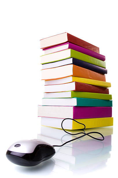 Corded mouse in front of tall stack of colorful books