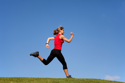 young woman running at the top of a hill